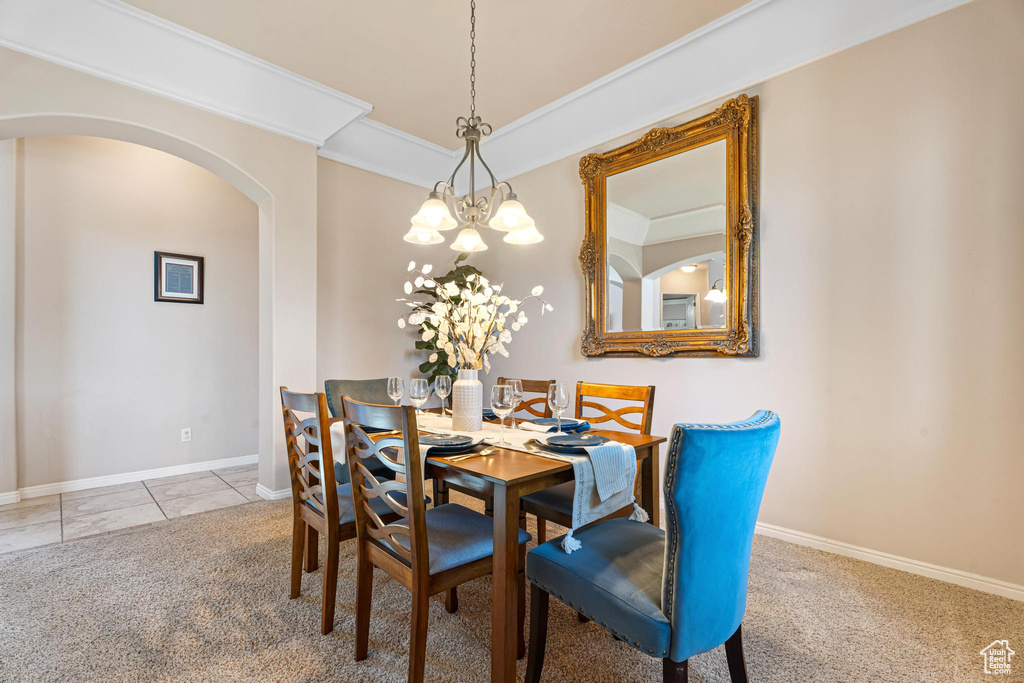 Dining room with a notable chandelier, light colored carpet, and ornamental molding