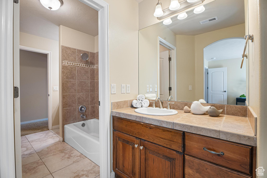 Bathroom with tile patterned flooring, vanity, and tiled shower / bath combo