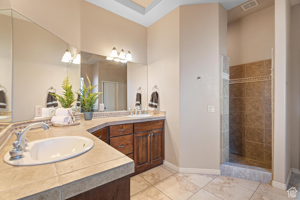 Bathroom with tile patterned floors, vanity, and tiled shower