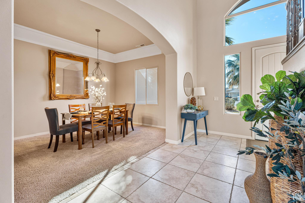 Carpeted dining area featuring ornamental molding and an inviting chandelier