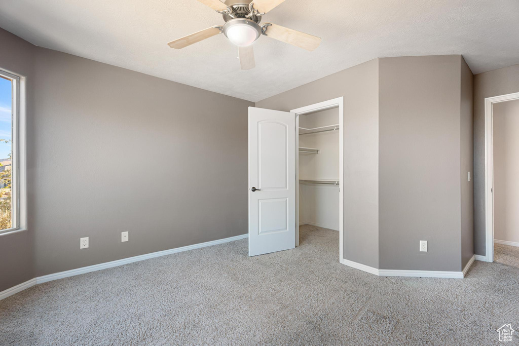 Unfurnished bedroom with ceiling fan, a closet, and light carpet