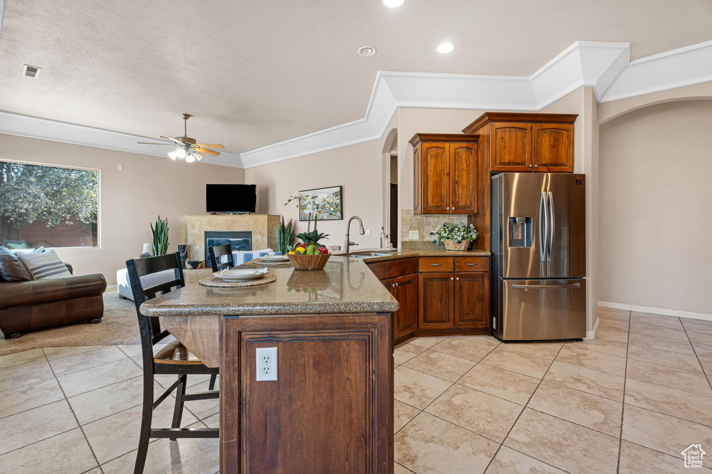 Kitchen featuring a tile fireplace, sink, kitchen peninsula, ceiling fan, and stainless steel fridge with ice dispenser