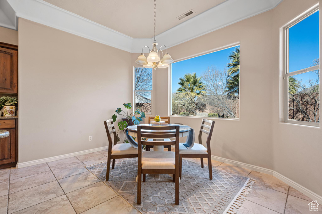 Tiled dining room featuring a raised ceiling, a chandelier, and ornamental molding