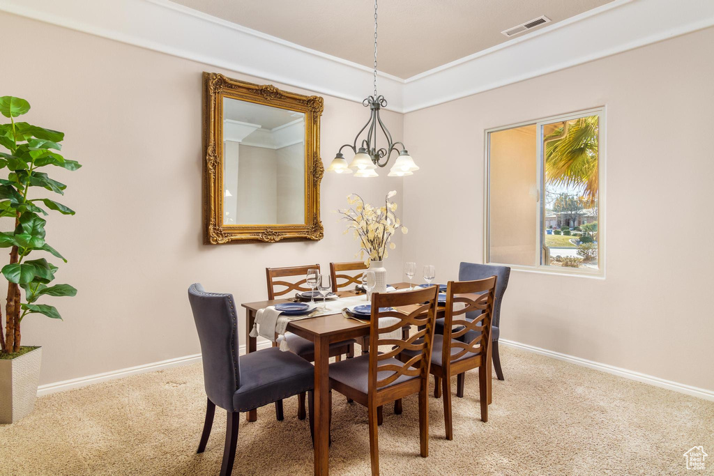 Carpeted dining space featuring a notable chandelier and crown molding