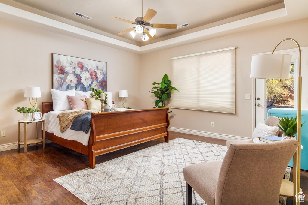 Bedroom with ceiling fan, dark hardwood / wood-style floors, and a raised ceiling