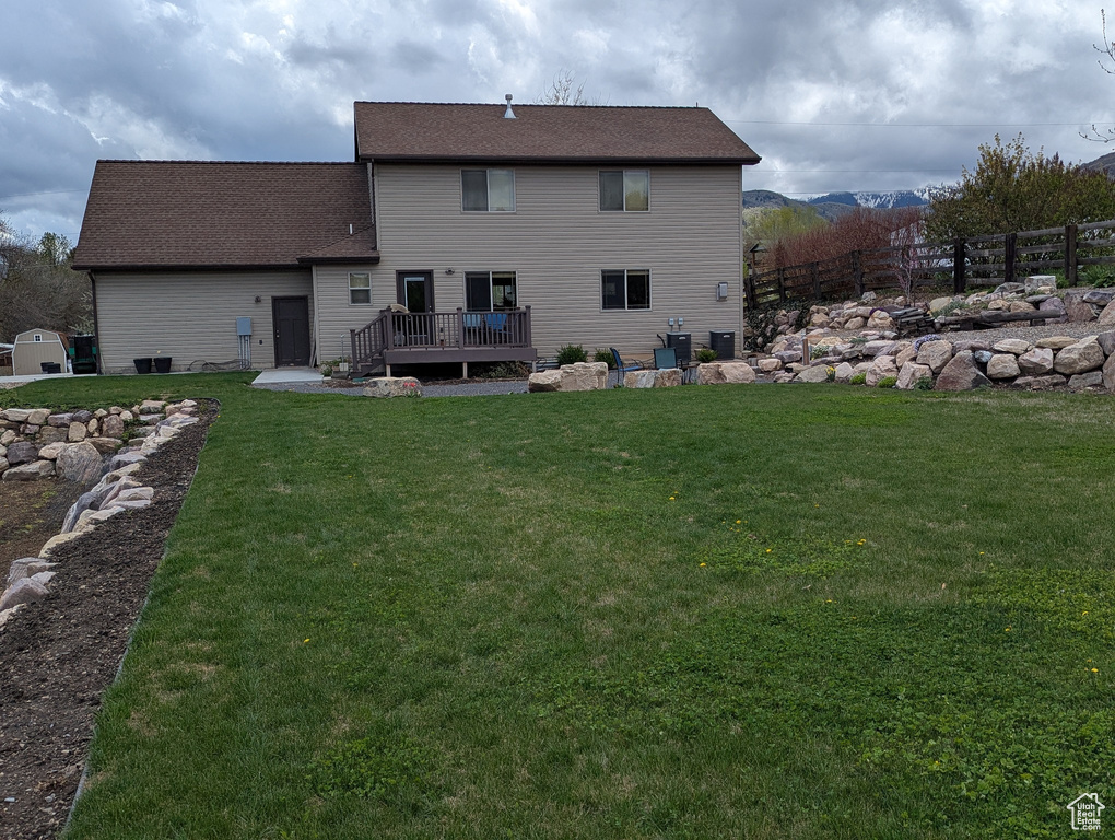 Back of property featuring a lawn, a wooden deck, and fence