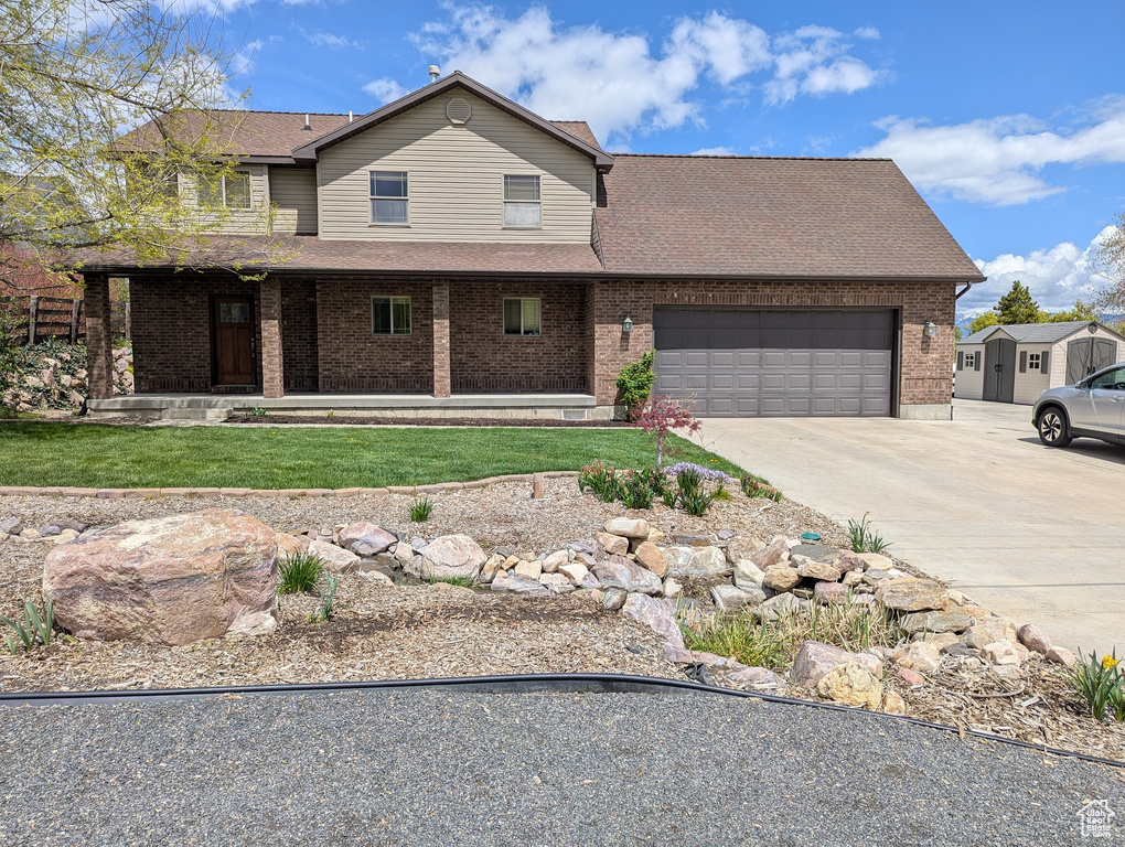 Traditional home with roof with shingles, a front lawn, brick siding, a garage, and driveway