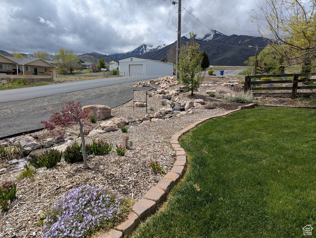 View of yard with a garage, a mountain view, fence, and driveway