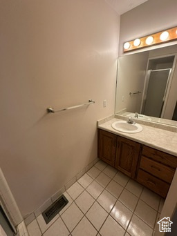 Bathroom with tile patterned flooring, vanity, and a shower with door