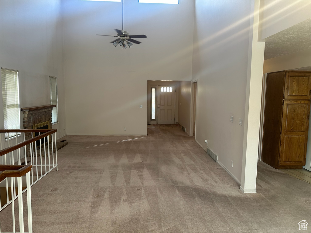 Interior space featuring ceiling fan, a towering ceiling, and a brick fireplace