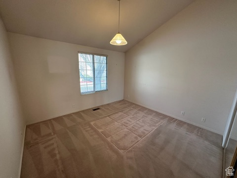 Empty room featuring carpet flooring and lofted ceiling