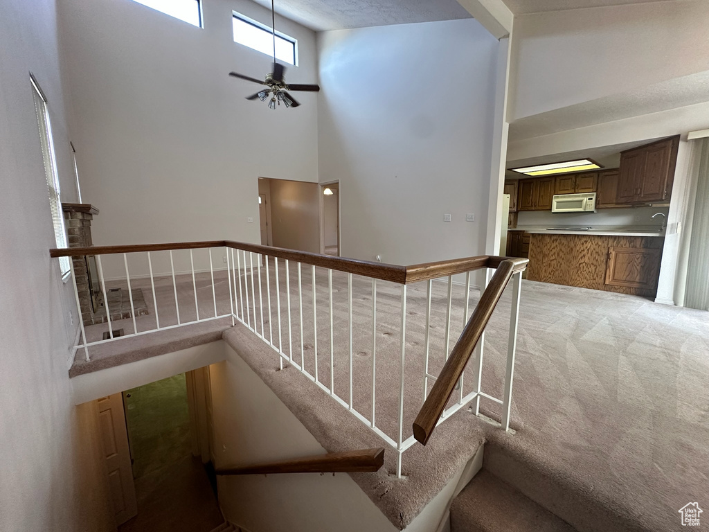 Stairway featuring carpet, ceiling fan, and a towering ceiling