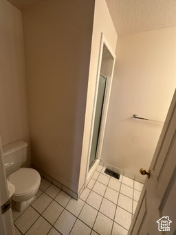 Bathroom featuring tile patterned flooring, toilet, and a textured ceiling