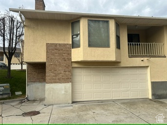 View of front facade featuring a garage and a balcony