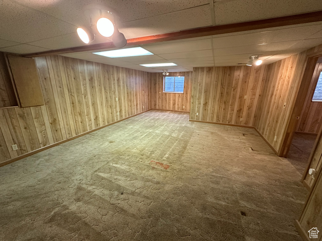 Basement with a paneled ceiling and carpet floors