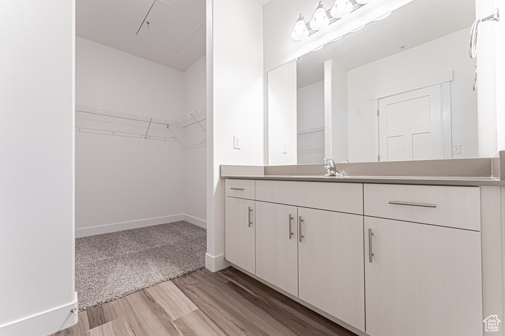 Bathroom featuring vanity, wood finished floors, a spacious closet, and baseboards