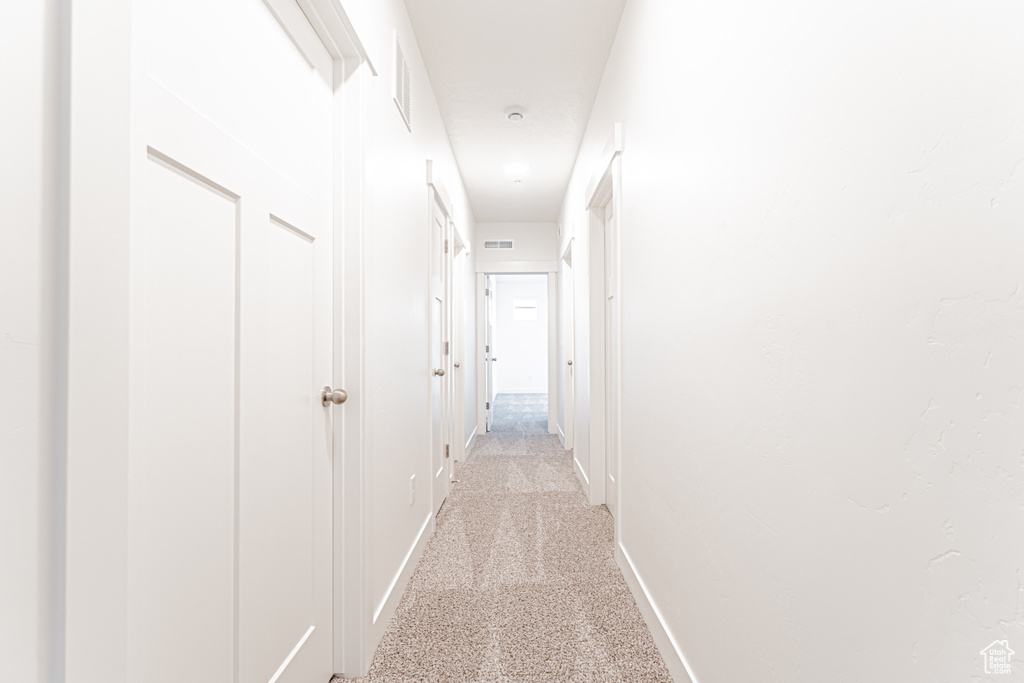 Hall with baseboards and light colored carpet