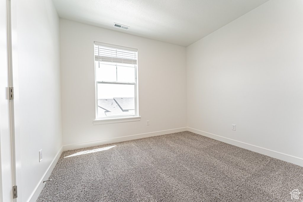 Spare room featuring carpet and baseboards