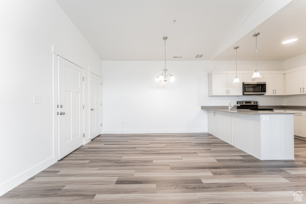 Kitchen with stainless steel appliances, a chandelier, baseboards, and white cabinets