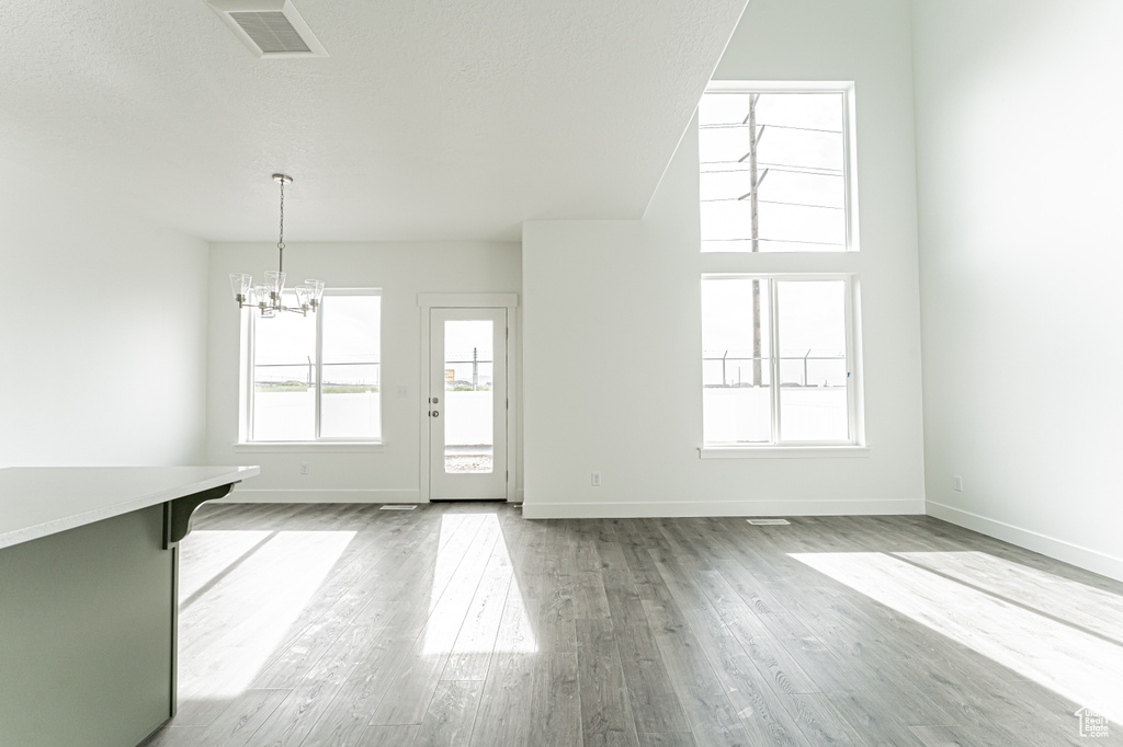 Unfurnished living room featuring a chandelier, wood finished floors, and baseboards