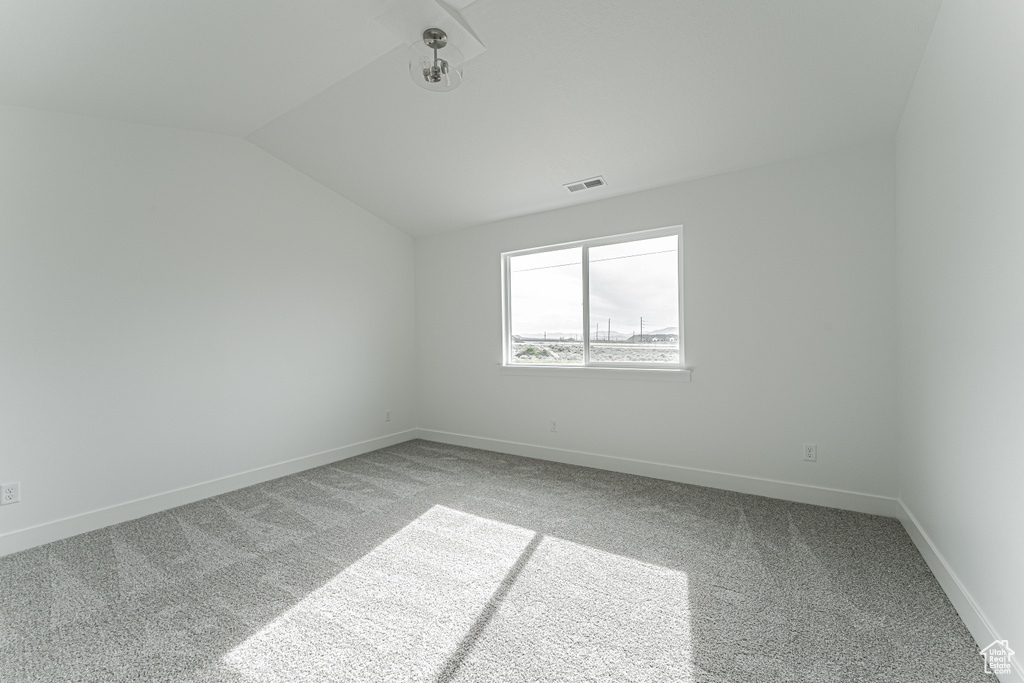 Carpeted empty room with vaulted ceiling and baseboards