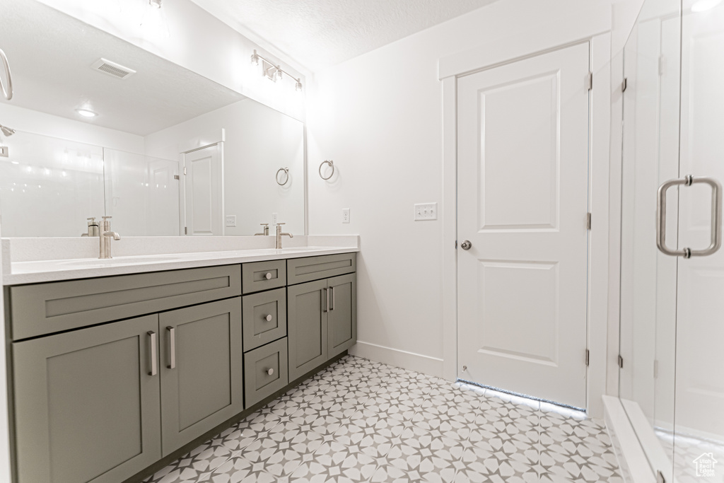 Bathroom featuring double vanity, a stall shower, tile patterned floors, and baseboards