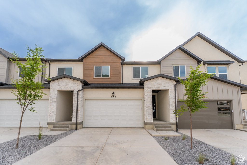 View of front of property featuring concrete driveway, stone siding, and an attached garage