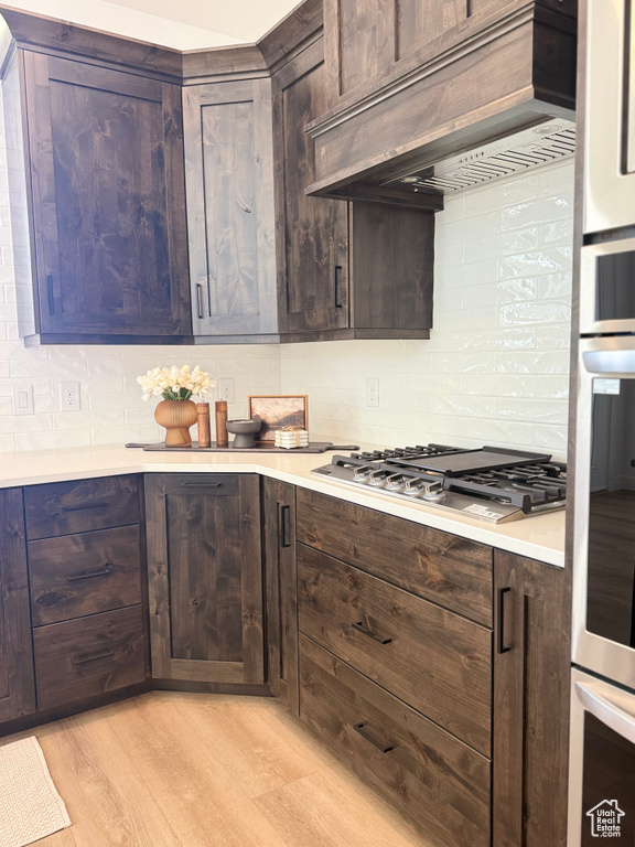 Kitchen featuring light countertops, premium range hood, decorative backsplash, and stainless steel appliances