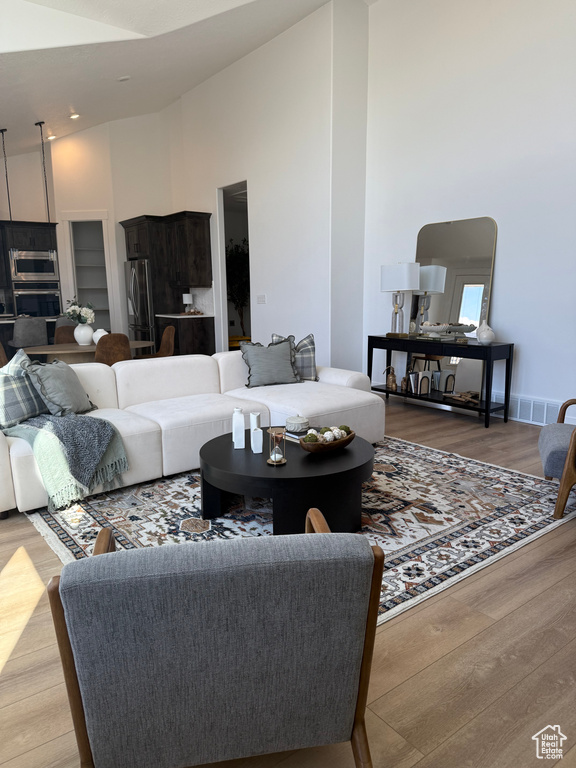 Living room featuring high vaulted ceiling, visible vents, and wood finished floors