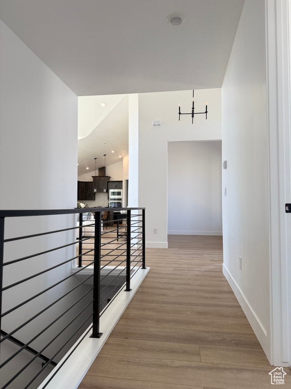 Hall with a notable chandelier, baseboards, an upstairs landing, and light wood-type flooring
