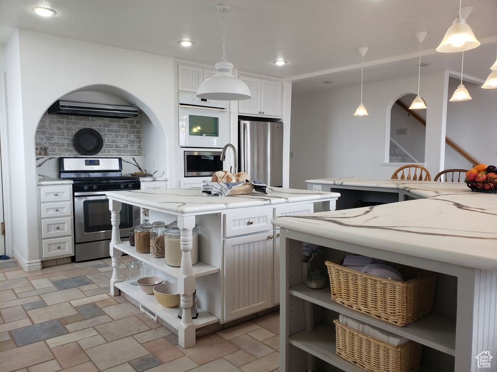 Kitchen featuring white cabinets, decorative light fixtures, and stainless steel appliances