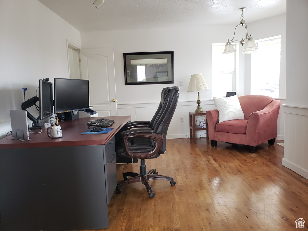 Office with light hardwood / wood-style flooring and a notable chandelier