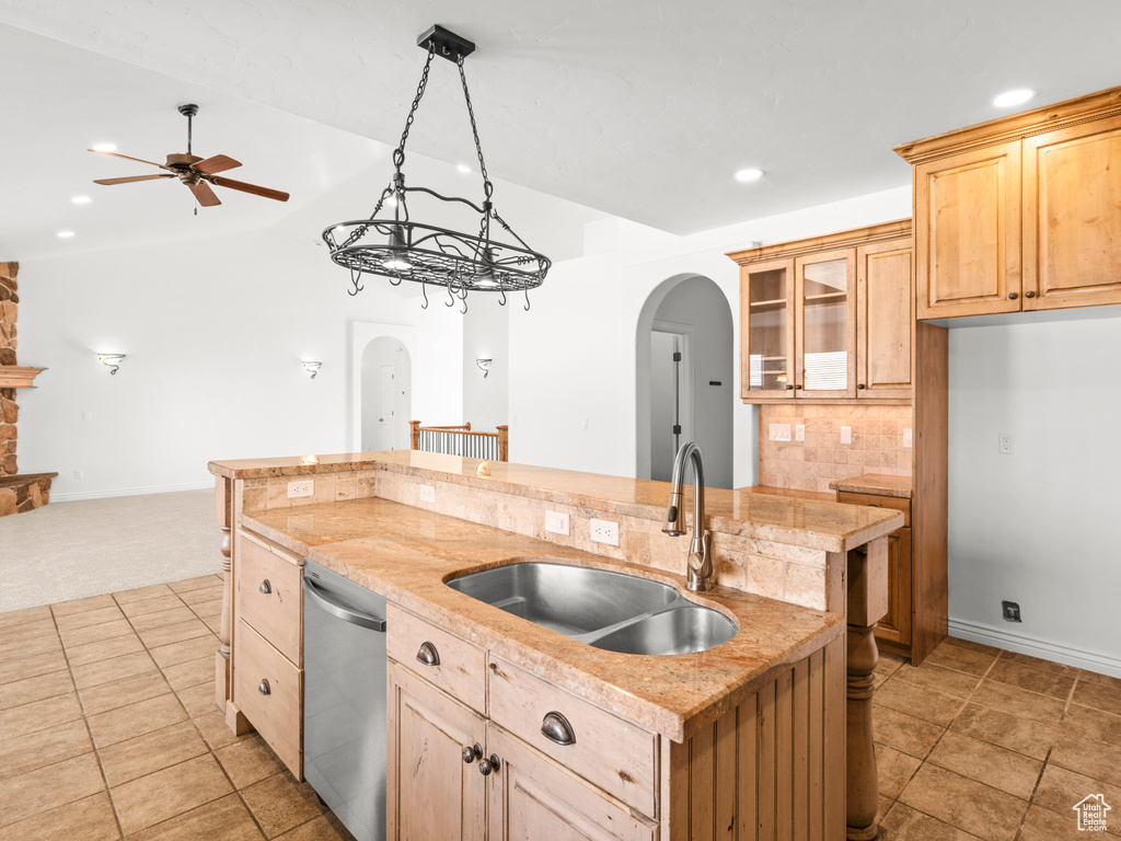 Kitchen with ceiling fan, dishwasher, sink, tasteful backsplash, and a kitchen island with sink