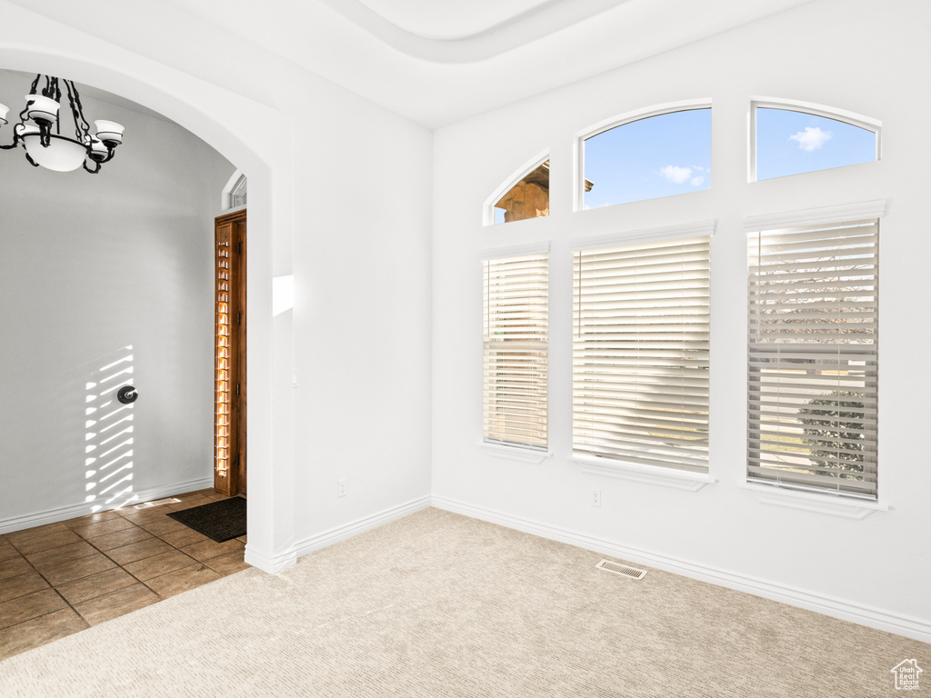 Tiled spare room featuring an inviting chandelier