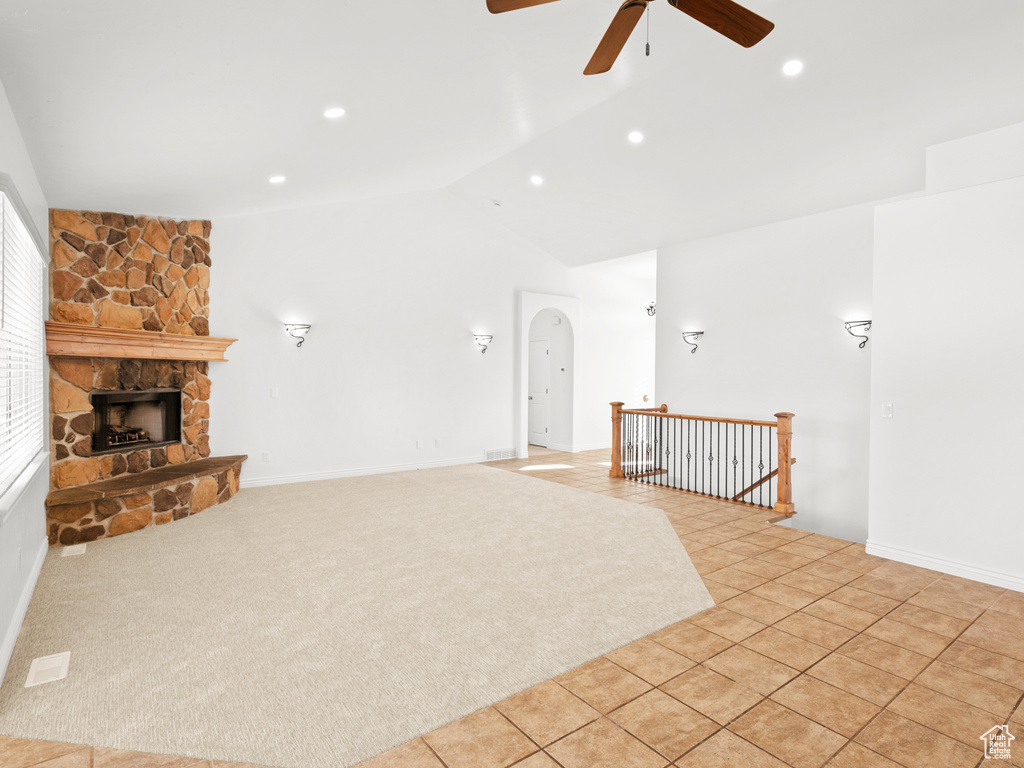 Unfurnished living room with ceiling fan, light tile patterned flooring, a fireplace, and vaulted ceiling