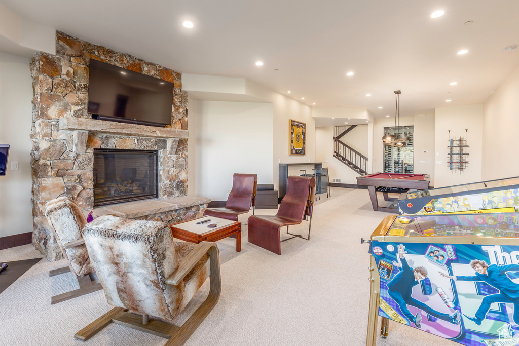 Living room featuring a stone fireplace, light carpet, and pool table