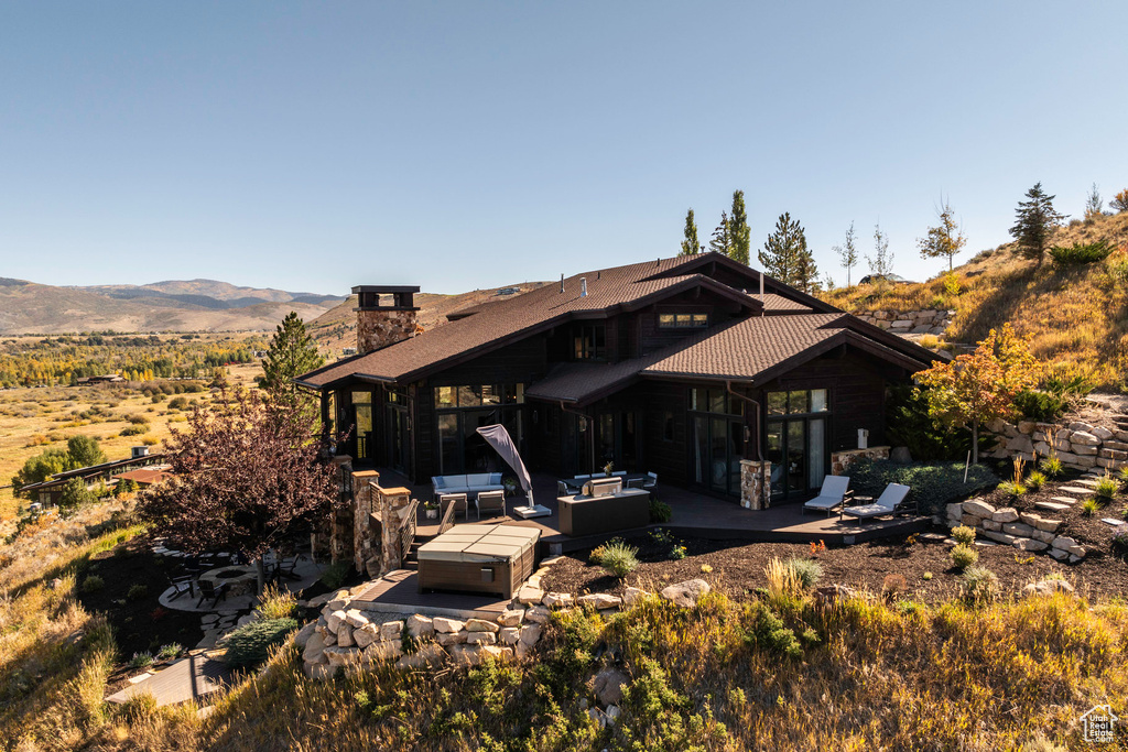 Back of house with a mountain view, outdoor lounge area, a hot tub, and a patio area