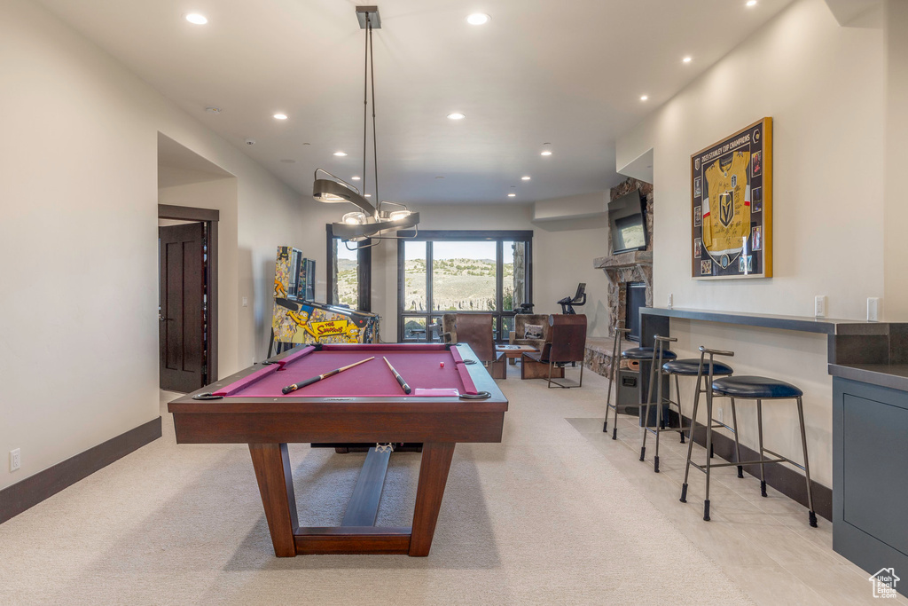 Recreation room featuring a stone fireplace, light colored carpet, and pool table