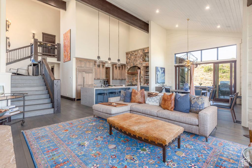 Living room featuring dark hardwood / wood-style flooring, a towering ceiling, a notable chandelier, and wood ceiling