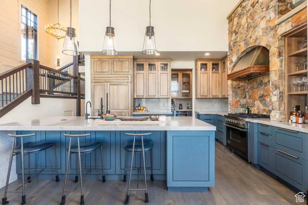 Kitchen featuring dark wood-type flooring, hanging light fixtures, tasteful backsplash, custom range hood, and high end appliances