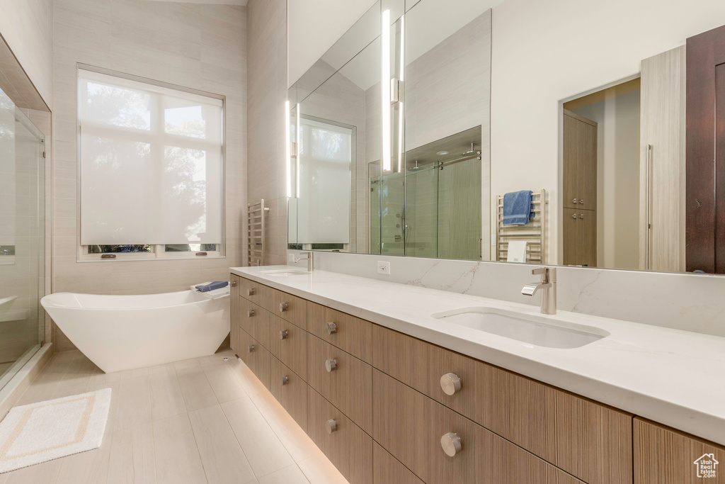 Bathroom with tile patterned flooring, vanity, separate shower and tub, and tile walls