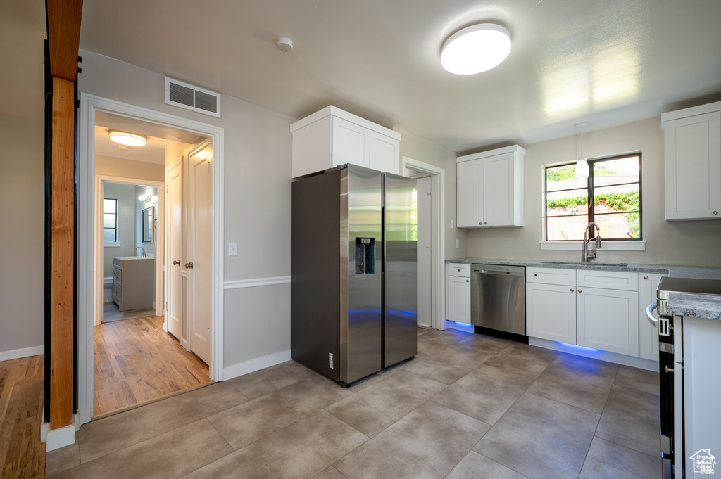 Kitchen with light stone counters, sink, white cabinets, and appliances with stainless steel finishes