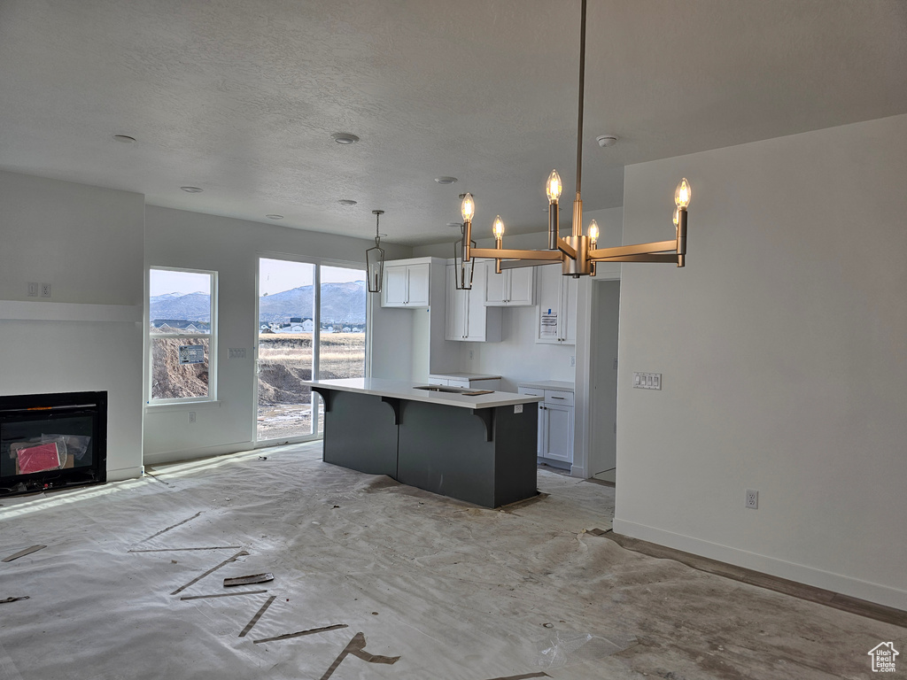 Kitchen with pendant lighting, a mountain view, a center island, a kitchen breakfast bar, and white cabinetry