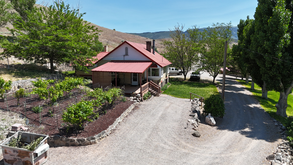 View of front of house with a porch, a chimney, a mountain view, metal roof, and dirt driveway