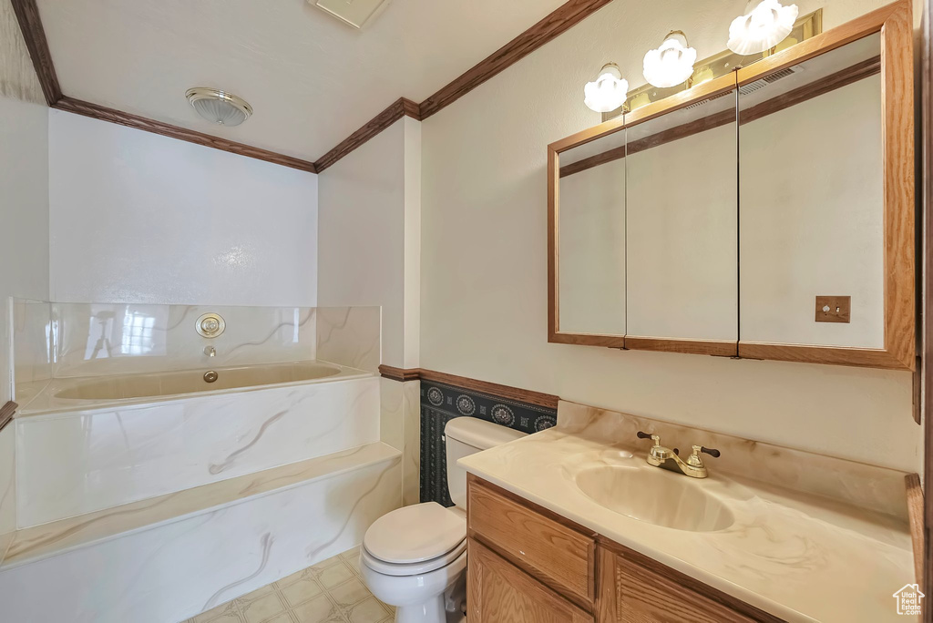 Bathroom with a bathing tub, crown molding, vanity, and toilet