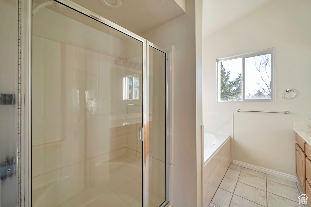 Bathroom featuring tile patterned flooring, vanity, and shower with separate bathtub