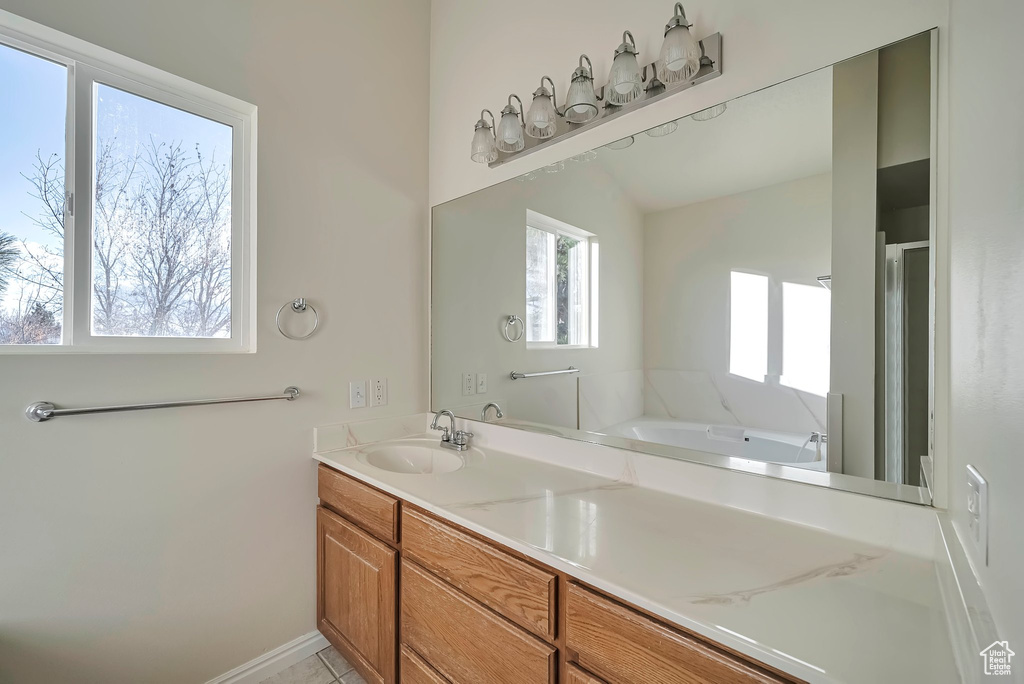 Bathroom featuring a wealth of natural light, vanity, and lofted ceiling