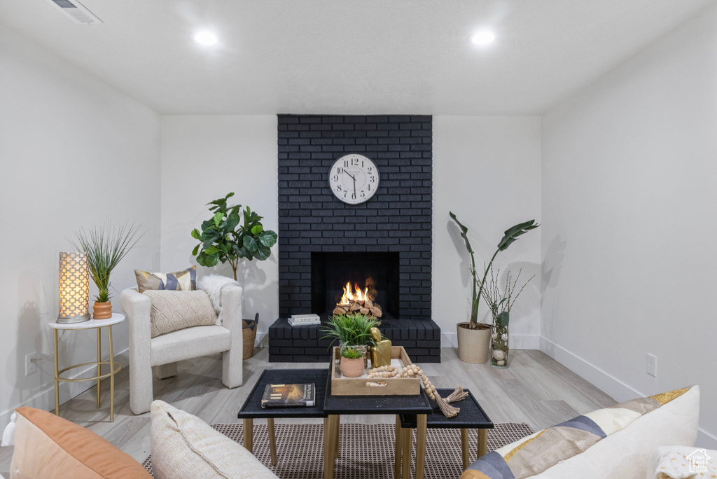 Living room with light hardwood / wood-style floors and a brick fireplace