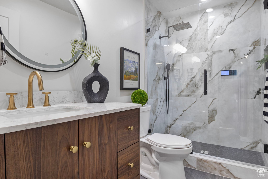 Bathroom with vanity, toilet, and a shower with shower door