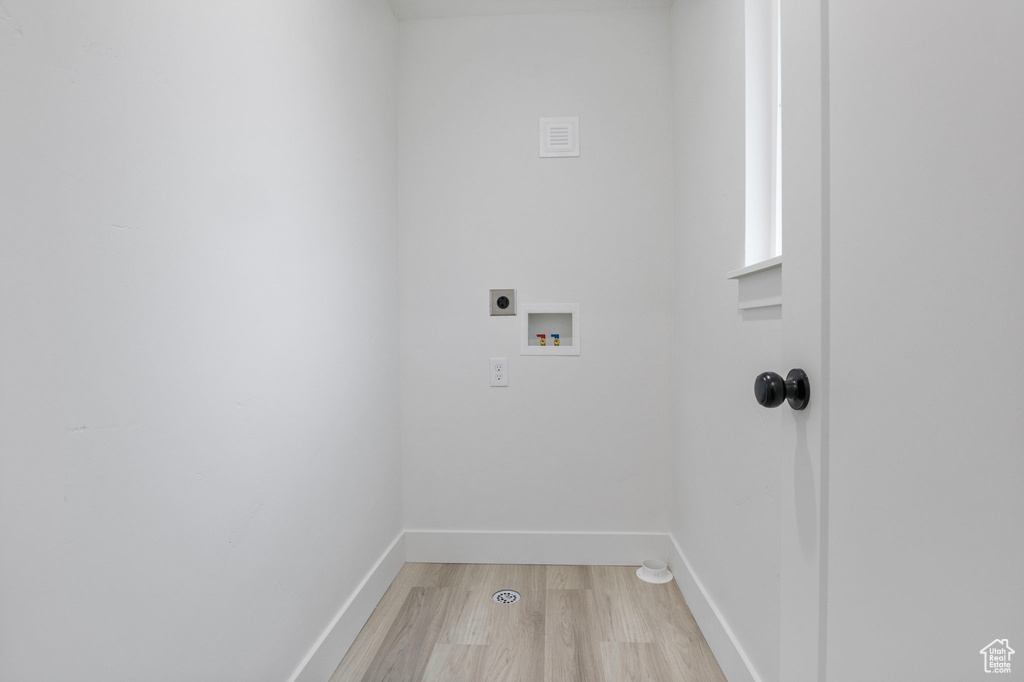 Laundry room with hookup for an electric dryer, washer hookup, and light wood-type flooring